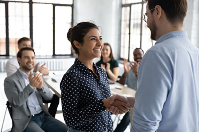 coworkers smiling at each other, shaking hands as if congratulations are being offered