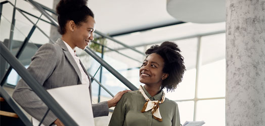 businesswoman talks to employee and guides her through office building.