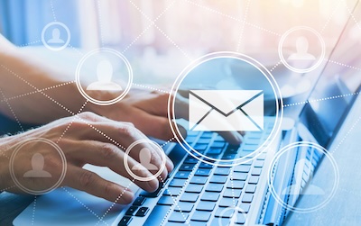 hands typing on keyboard with email icons floating in space above