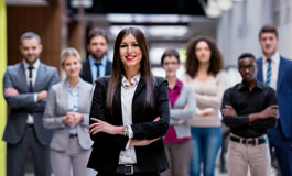 Female executive, arms crossed, with team of employees in background