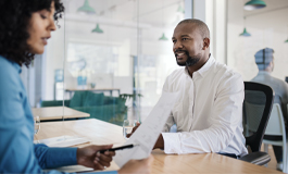 Woman at desk reviewing paper work with associate 