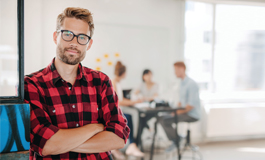 Man in office looking at camera; team behind him